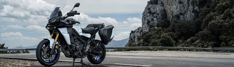 Yamaha motorcycle parked on the side of a road with coastal cliffs and trees in the background.