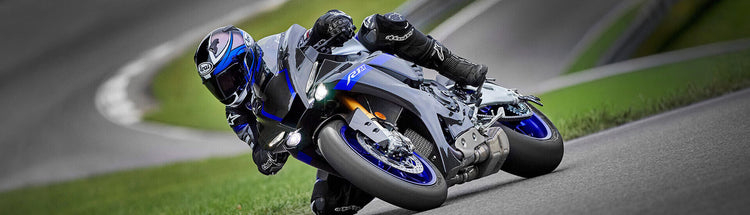 Motorcyclist riding a Yamaha R1 sportsbike on a racetrack with a blurred background.